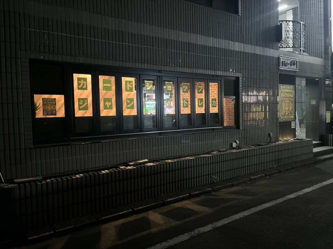 夜の店舗外観、窓に灯る「ジャングルトレカ」の文字